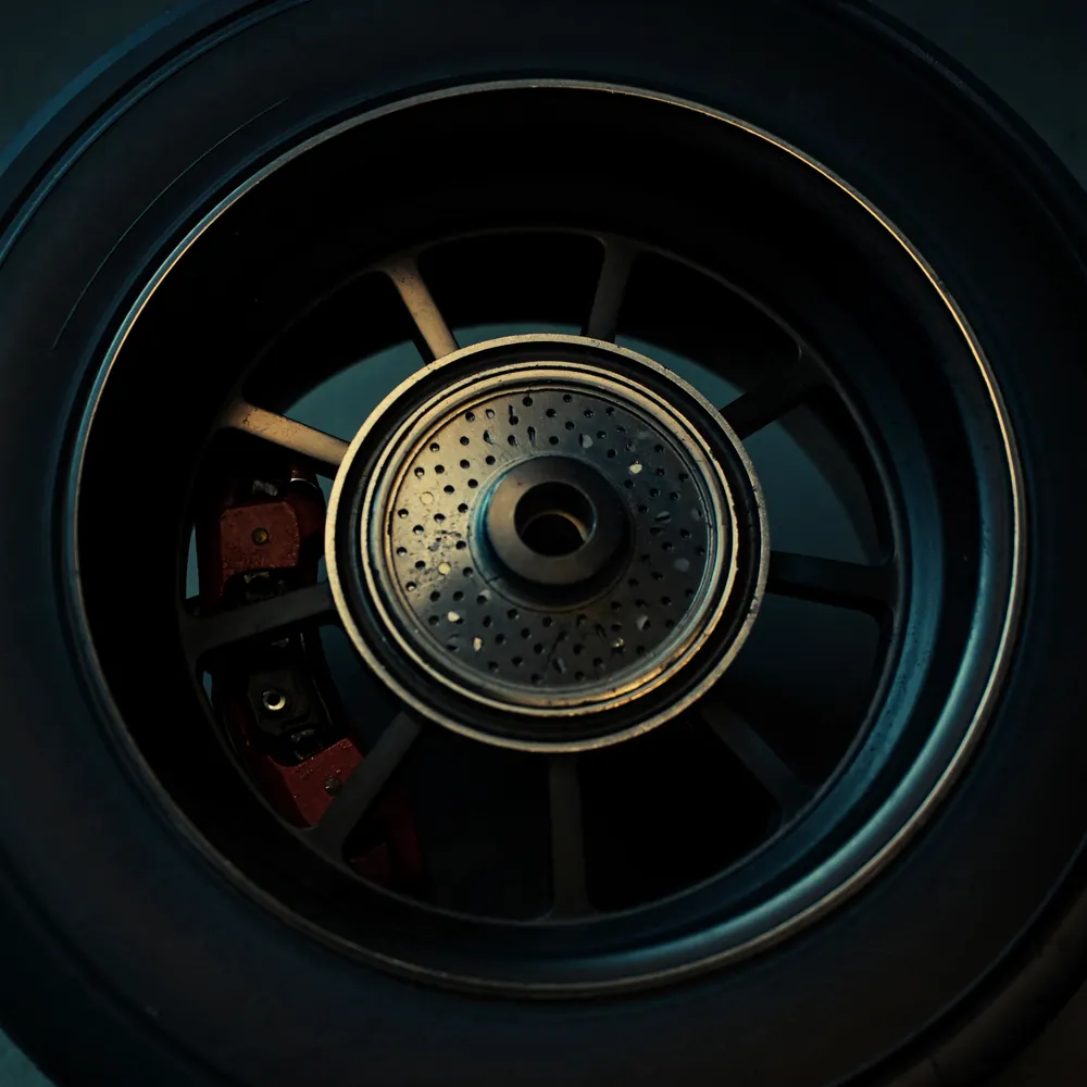 Close-up of an alloy wheel and drilled brake disc with a red brake caliper behind the spokes